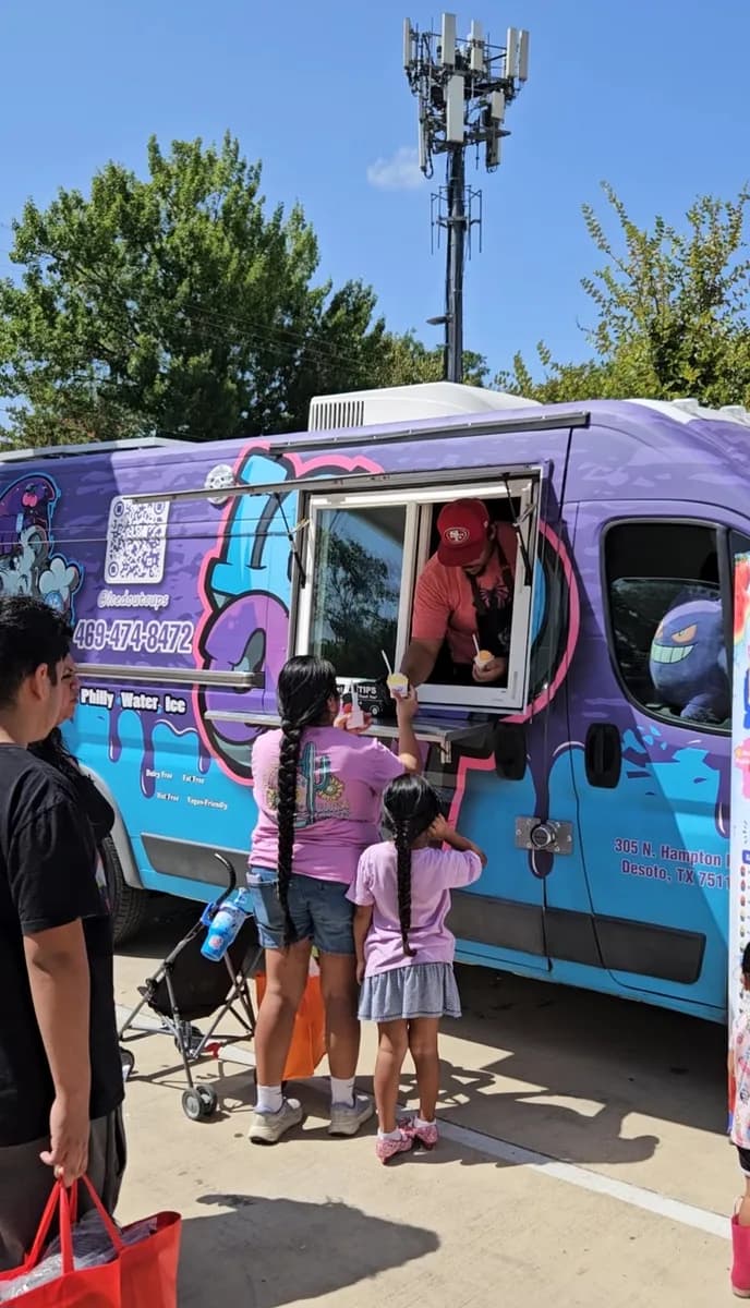 A family receiving cups of Iced Out water ice from the truck at a Behind Every Door community event