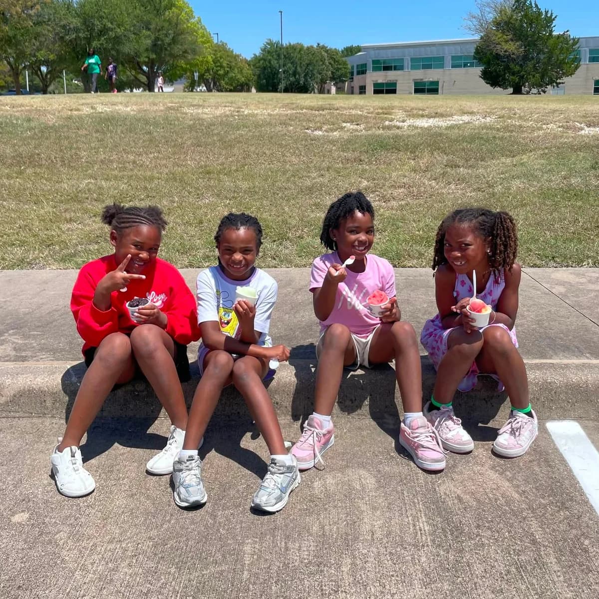 Campers sitting together enjoying cups of Iced Out water ice at a Cedar Hill Action Team event