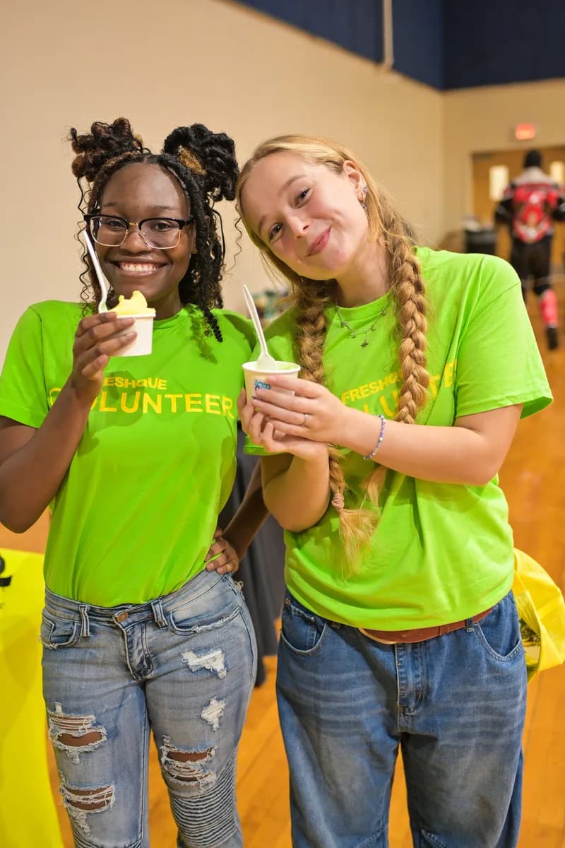 FreshQue volunteers smiling with cups of Iced Out water ice at a back-to-school resource event