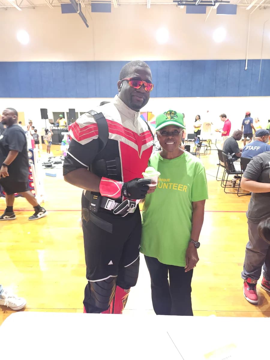 A volunteer and guest posing with Iced Out water ice at a Mercy Street Dallas community event