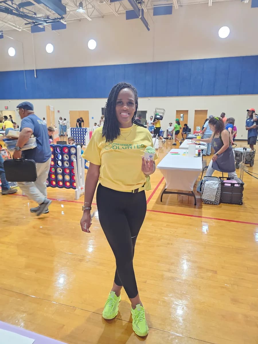 A volunteer smiling with a cup of Iced Out water ice at a Mercy Street Dallas event
